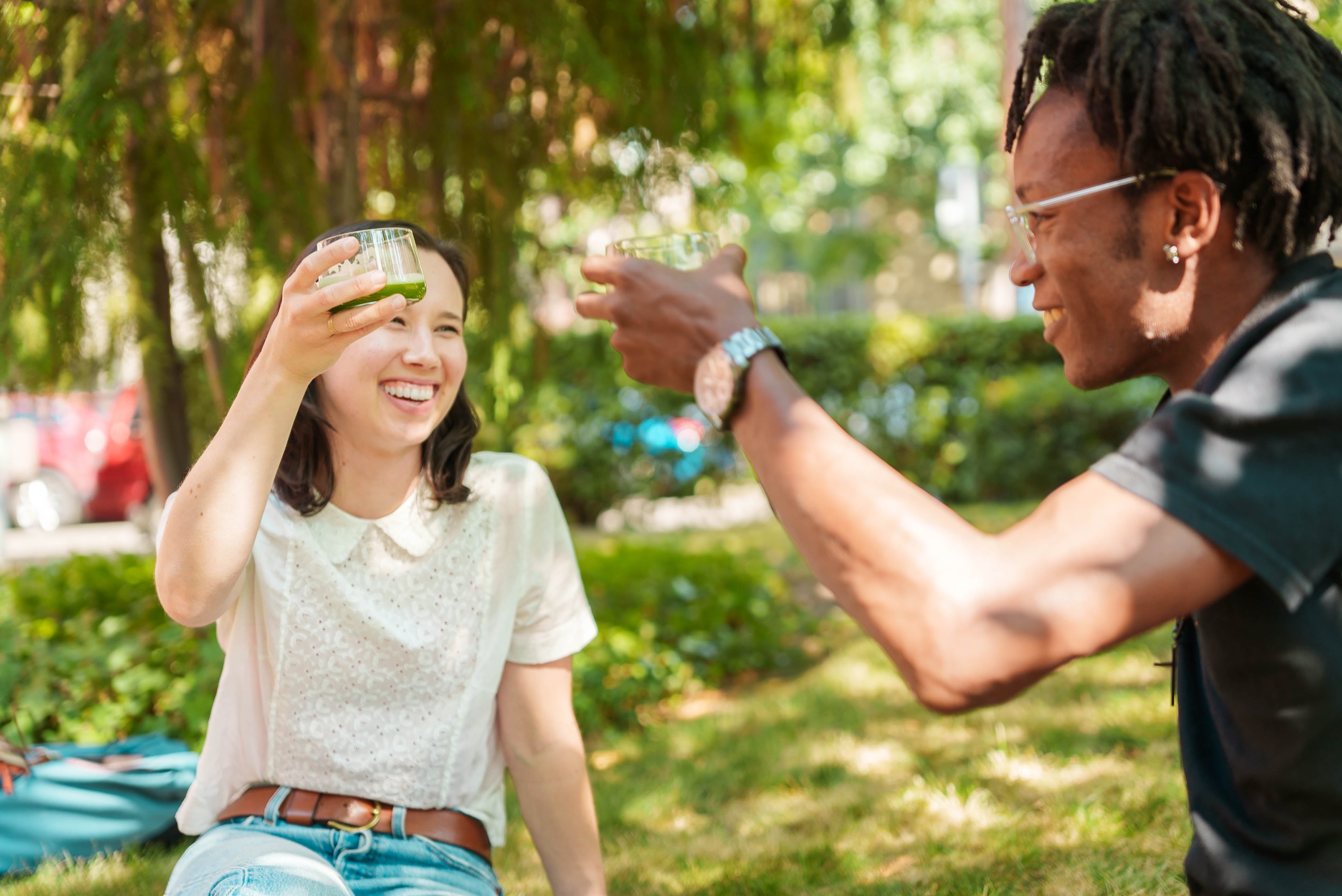 Friends drinking matcha from glass cups outside on the grass