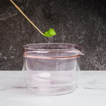 A matcha scoop with matcha powder above a glass container