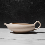 Beige ceramic yuzamashi teapot on a marble surface with a dark background