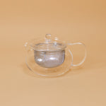 Japanese glass tea pot by Hario sits on a yellow background